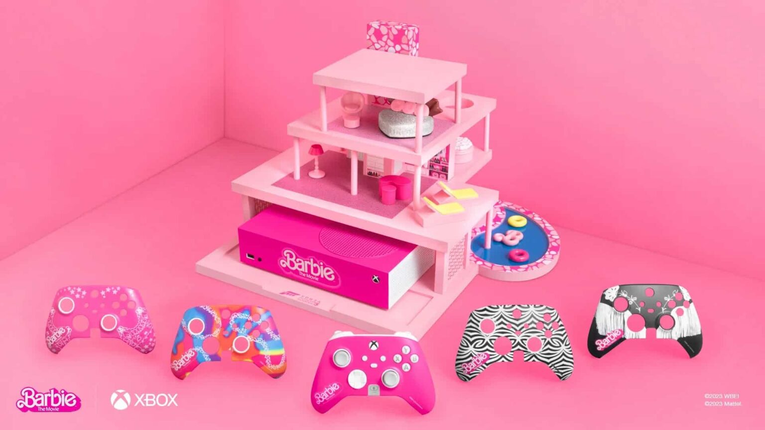 Console Xbox Series S rosa da Barbie com casinha cor-de-rosa ao lado e cinco controles temáticos em tons de rosa, estampas zebra e tie-dye