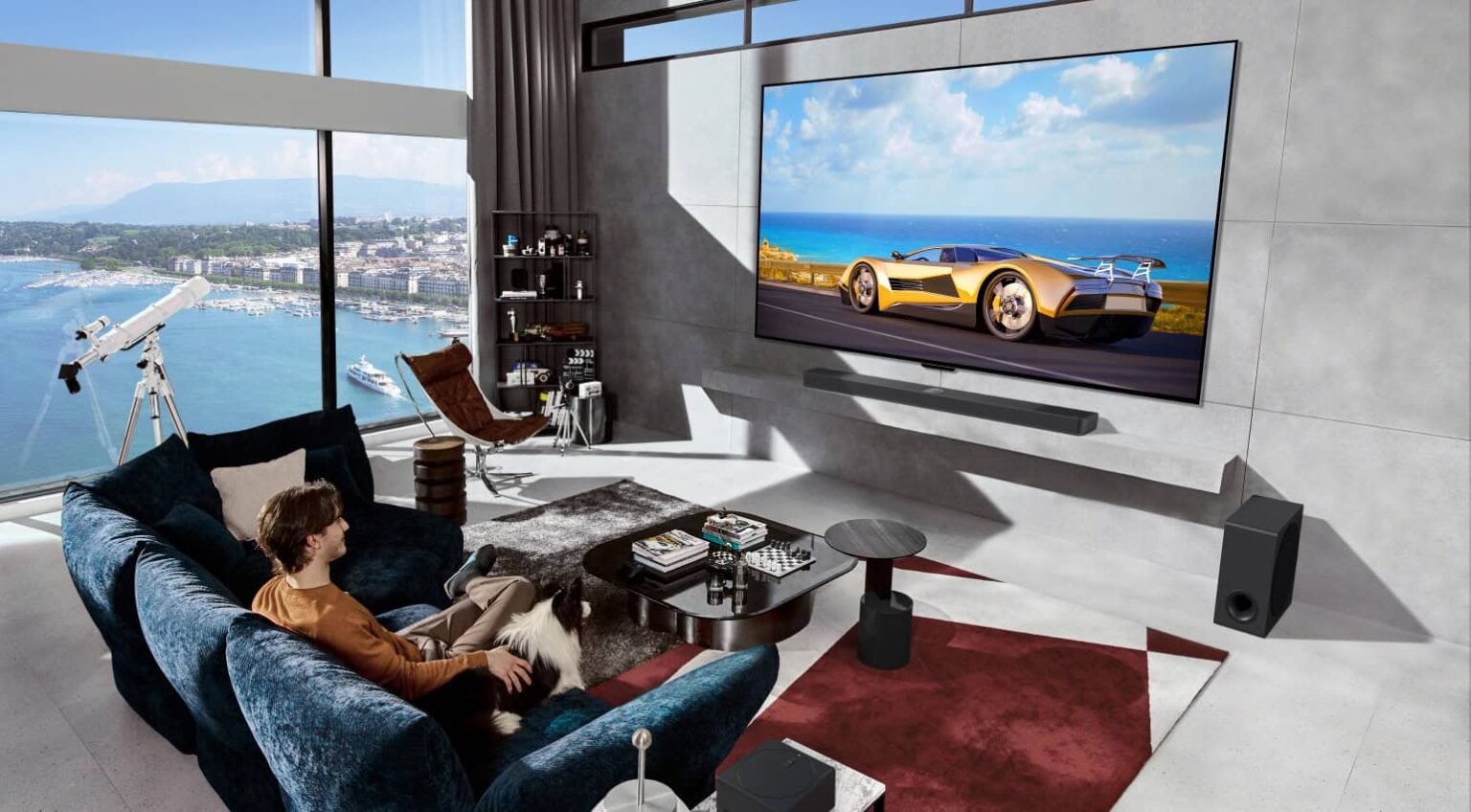 Sala de estar moderna com TV OLED de tela grande exibindo um carro esportivo dourado, barra de som e subwoofer, e um homem de camiseta laranja no sofá azul com…