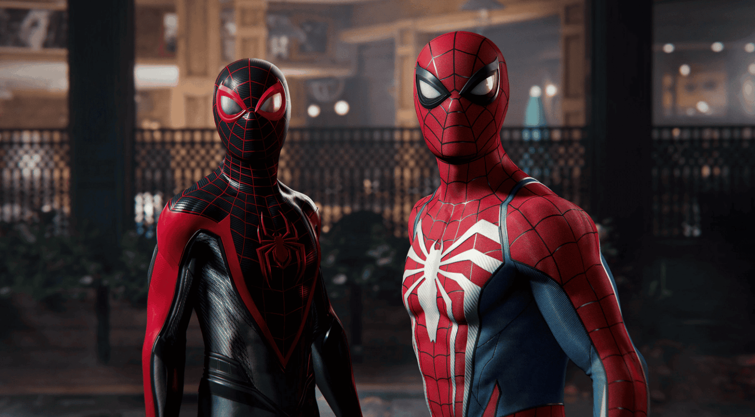 Captura de cena do jogo Marvel's Spider-Man 2 com dois Homem-Aranha lado a lado, um com traje preto e vermelho e outro com traje vermelho e azul, em cenário ur…