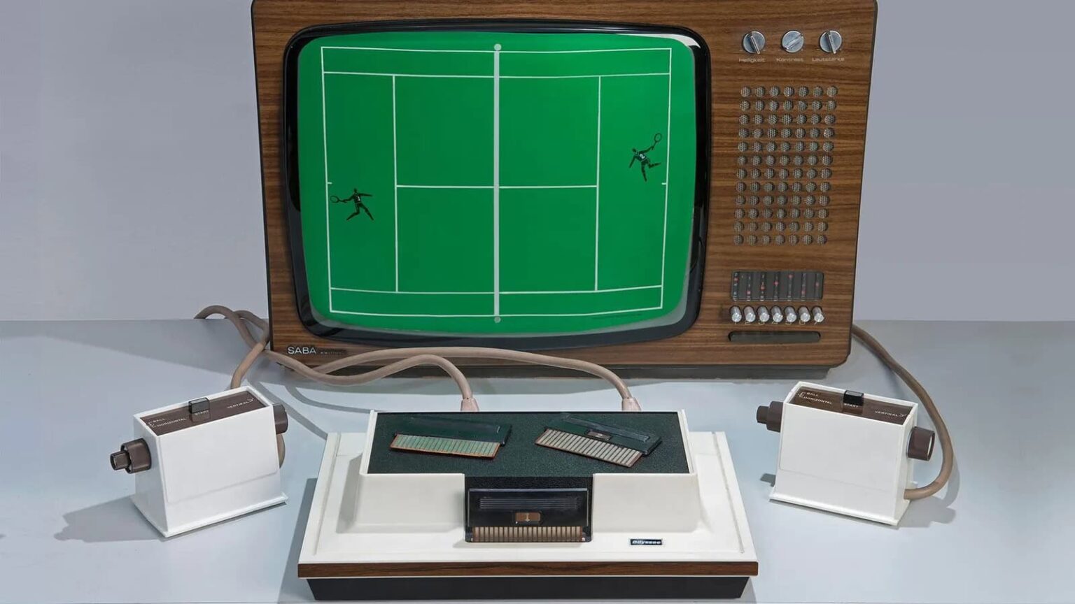 Console Magnavox Odyssey com TV de madeira exibindo jogo de tênis na tela verde, com dois controles brancos conectados e cartuchos sobre a base