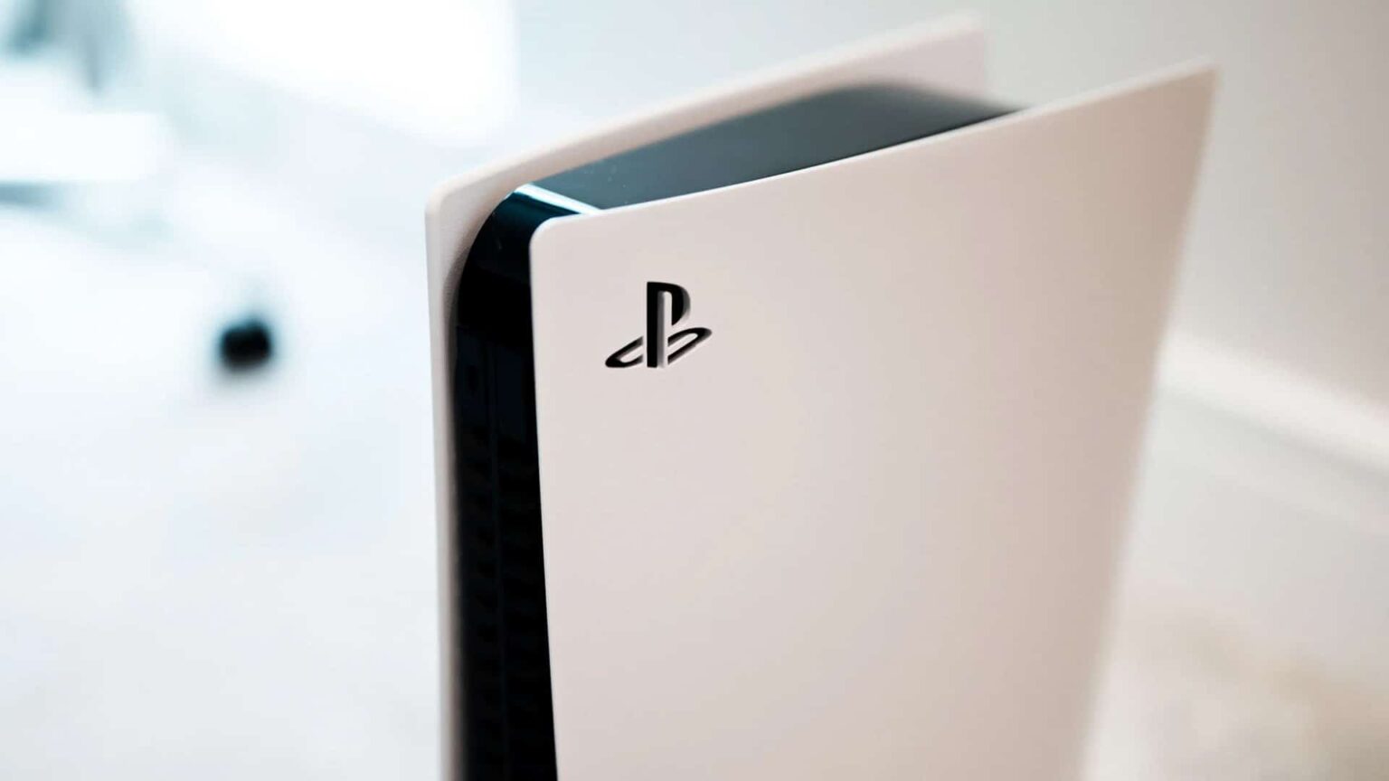 Console PlayStation 5 branco em posição vertical, com o logotipo PlayStation em destaque na lateral e fundo desfocado