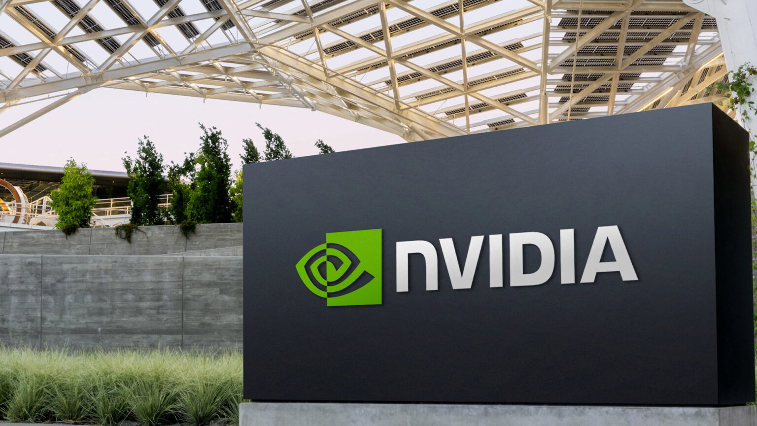 Placa de identificação da Nvidia em frente à sede da empresa, com o logotipo verde e o nome em letras brancas sob uma estrutura metálica com cobertura de painé…