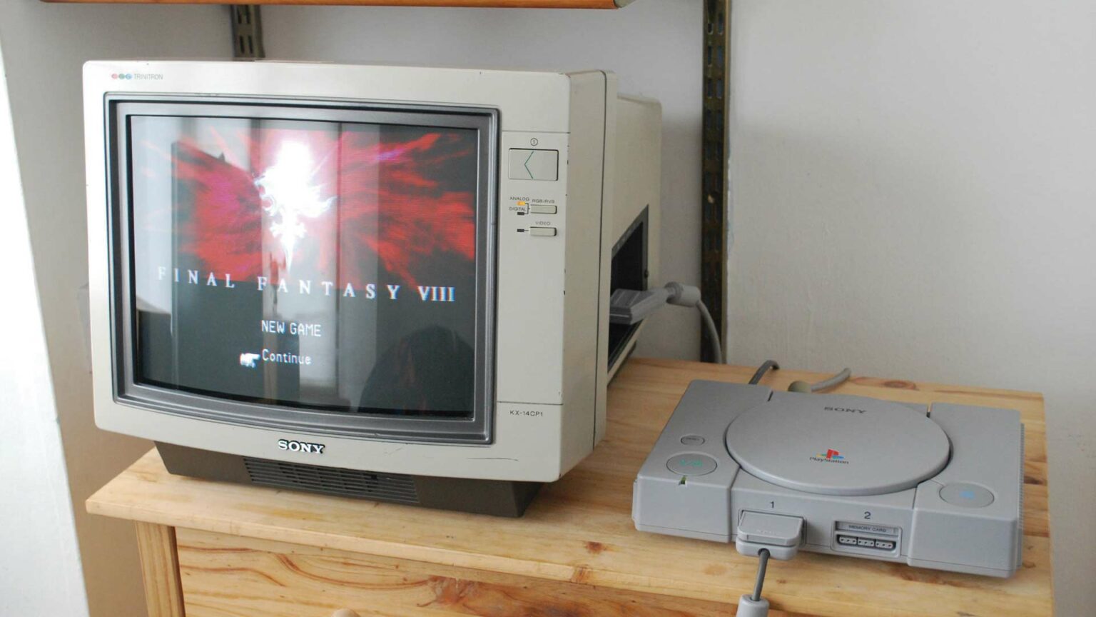 Console PlayStation 1 ao lado de um monitor de tubo Sony exibindo a tela inicial de Final Fantasy VIII, com as opções New Game e Continue