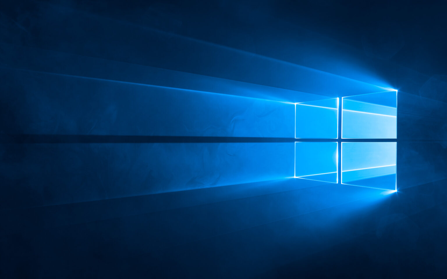 Logotipo do Windows 10 formado por janelas iluminadas em azul sobre fundo escuro, com feixes de luz