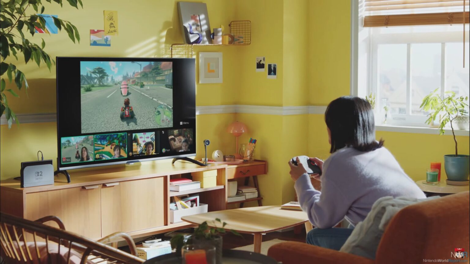 Pessoa jogando Mario Kart em um Nintendo Switch 2 numa sala amarela, com a tela da TV mostrando a corrida e quatro janelas de chat de vídeo