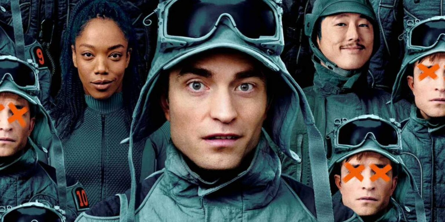 Grupo de astronautas em trajes verde-acinzentados e capacetes com viseira, um deles no centro olhando para frente, alguns com grandes X laranjas sobre o rosto