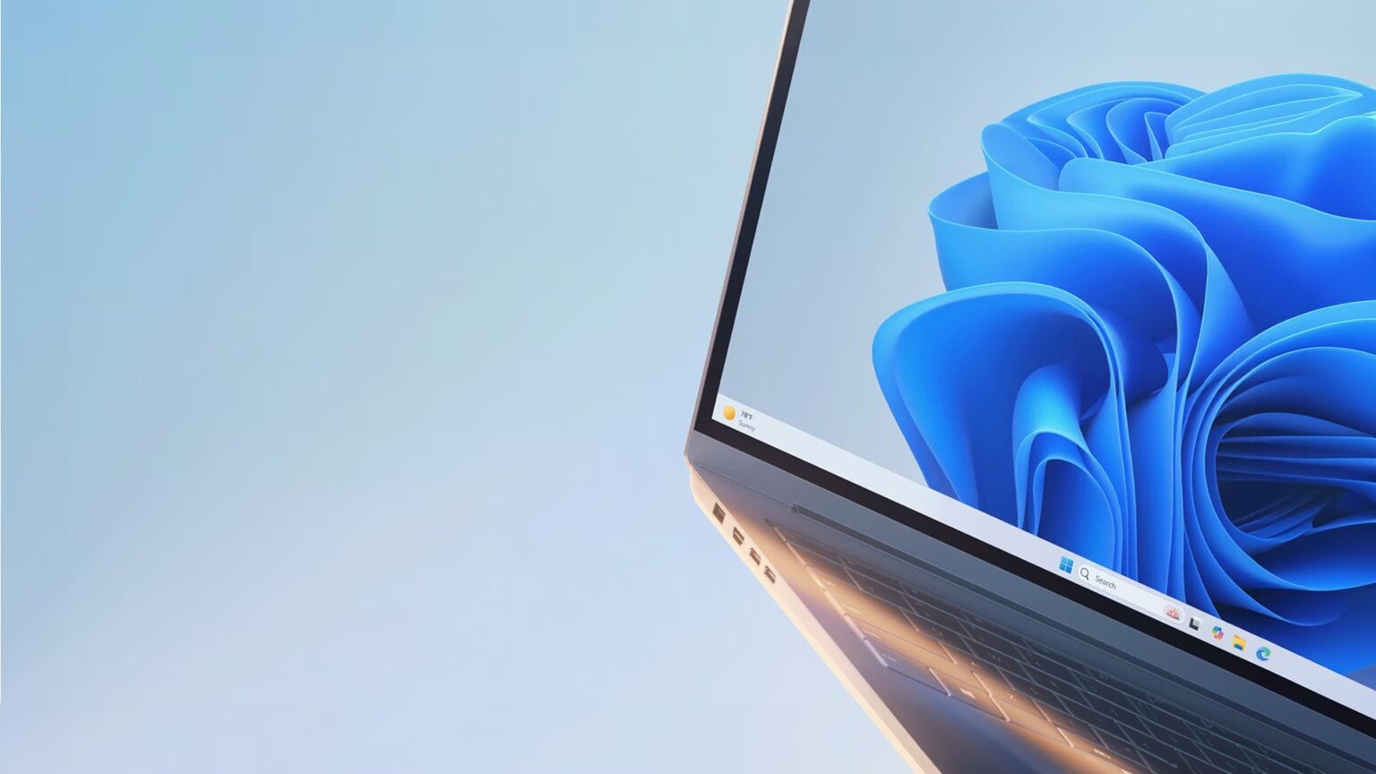 Notebook com tela aberta exibindo o papel de parede azul do Windows 11 e a barra de tarefas centralizada na base da tela