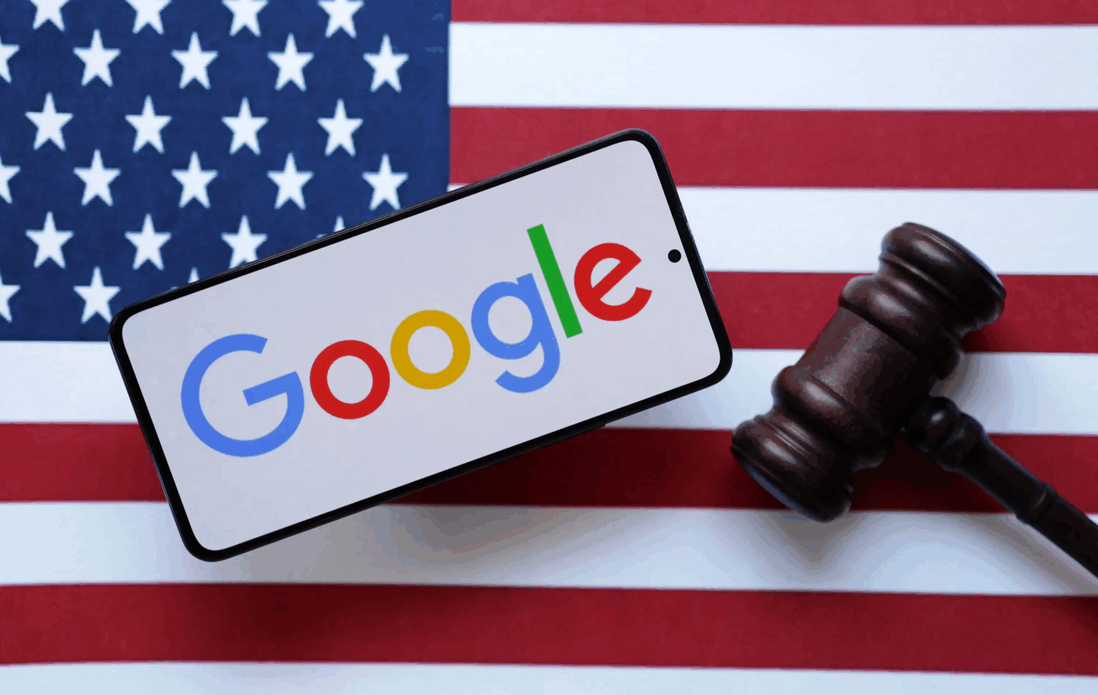 Smartphone exibindo o logo do Google sobre a bandeira dos Estados Unidos, ao lado de um martelo de juiz de madeira
