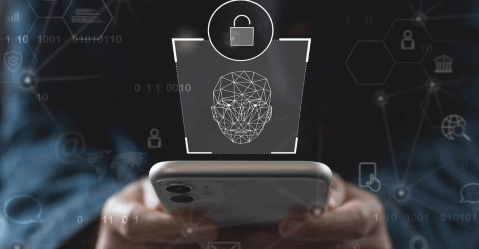 Mãos segurando smartphone com ilustração holográfica de reconhecimento facial e ícone de cadeado desbloqueado, representando segurança biométrica