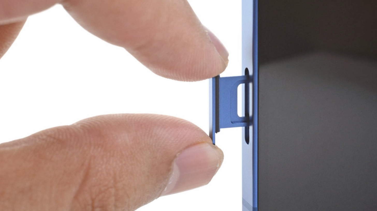 iPhone 17 Air não será lançado na China por causa da ausência de recurso valioso no país 1 Mão segurando a borda de smartphone azul com bandeja SIM parcialmente ejetada da lateral do aparelho