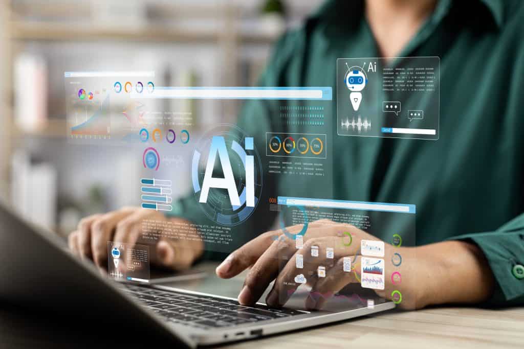 Redações com IA são fáceis de identificar e perdem autenticidade, diz estudo 1 Pessoa trabalhando em notebook com interfaces holográficas e símbolos de inteligência artificial visíveis
