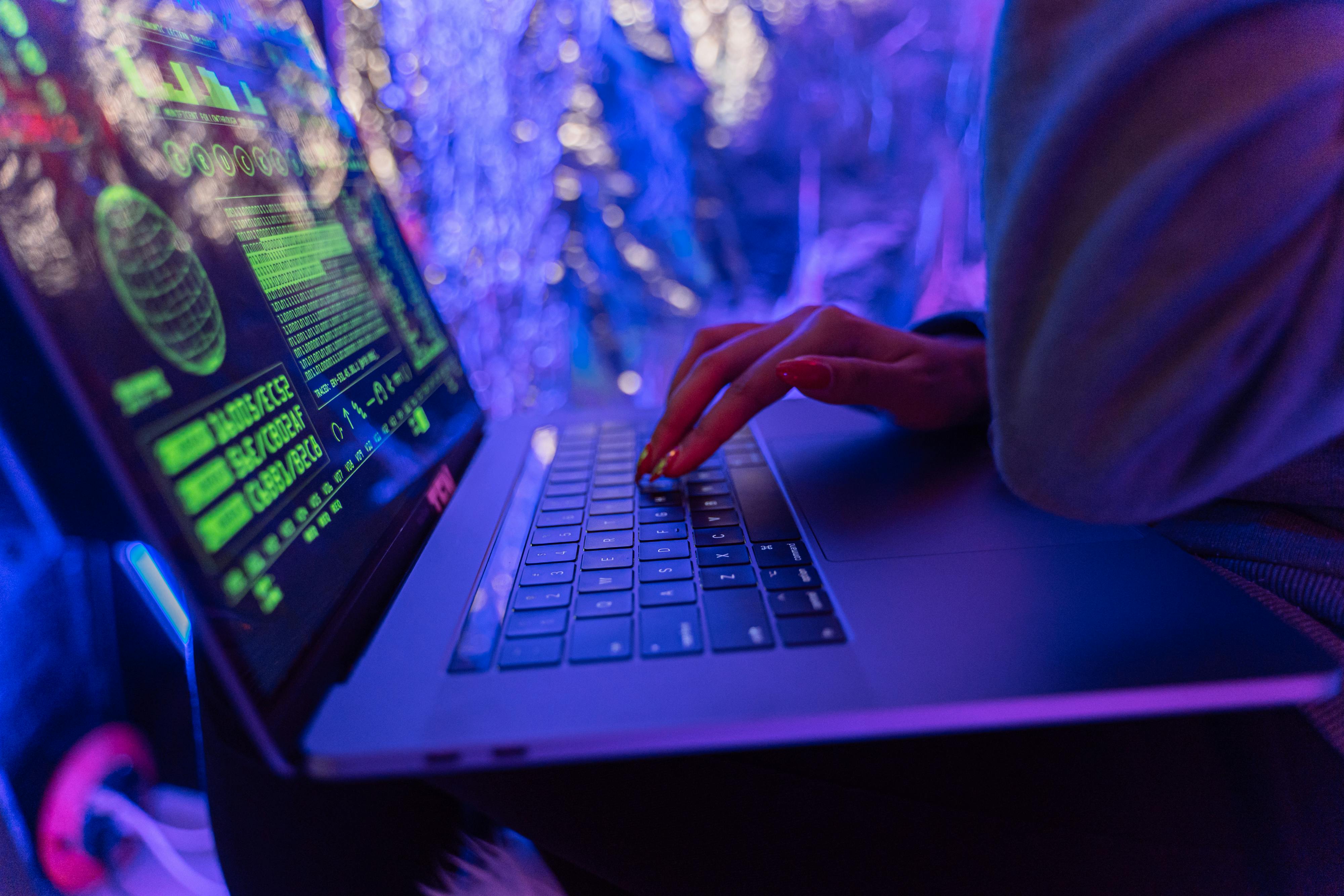 Recorde: Maior ataque DDoS da história teve força de 1 milhão de streams 4K 1 Pessoa digitando em laptop com interface gráfica de segurança cibernética na tela
