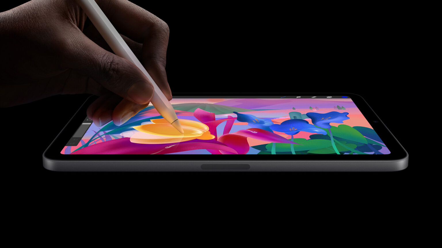 Mão usando caneta stylus branca para desenhar sobre a tela colorida de um iPad com ilustração de flores azuis e rosas em fundo de degradê