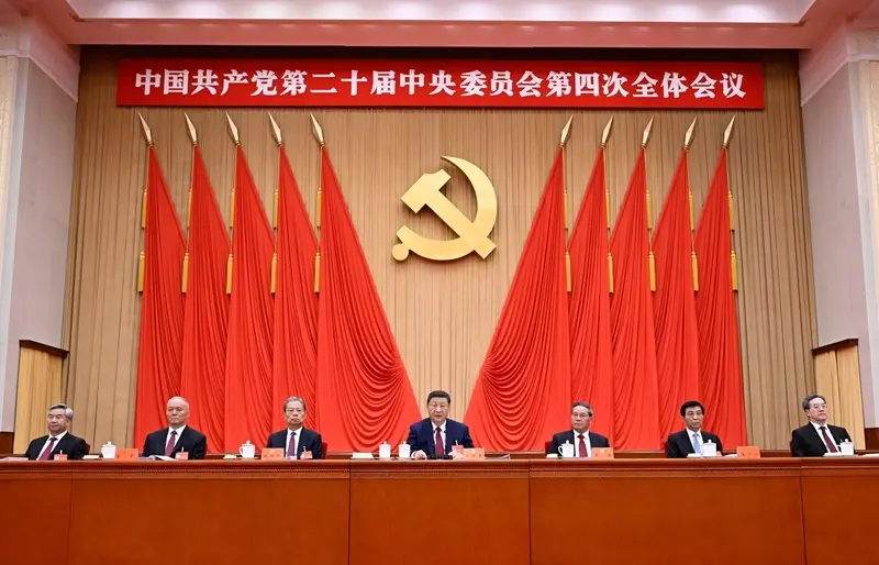 China redefine o futuro com plano de 5 anos focado em IA e semicondutores 4 Reunião oficial do Comitê Central do Partido Comunista Chinês com emblema dourado e bandeiras vermelhas ao fundo