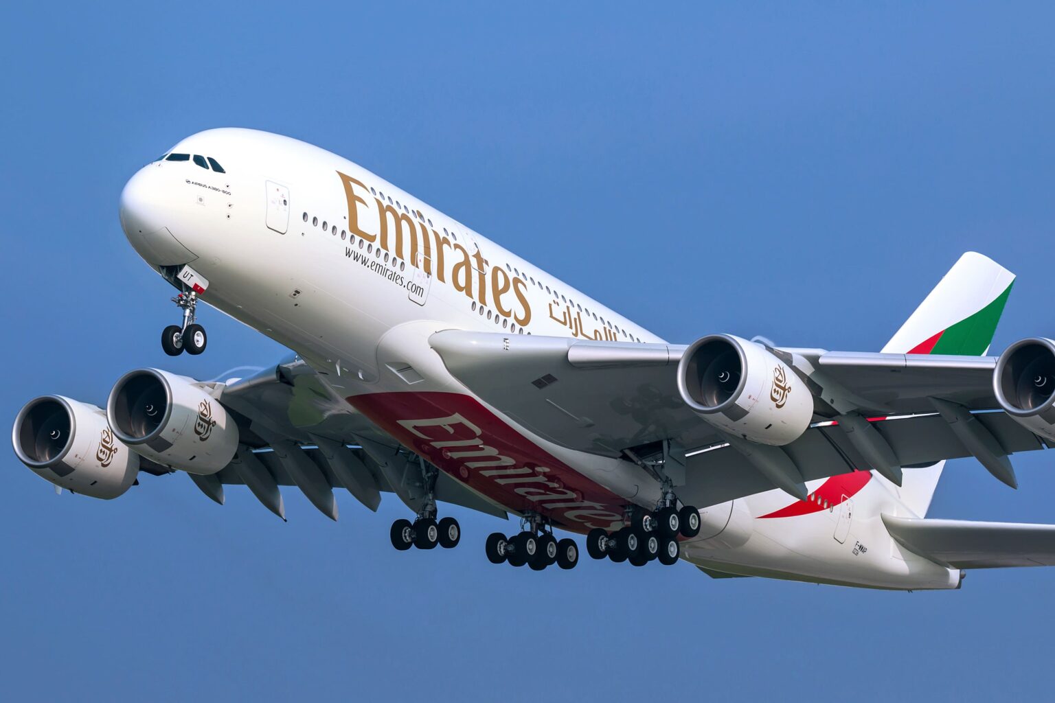 Avião Airbus A380 da Emirates decolando contra o céu azul, com o logotipo da companhia na fuselagem e os motores visíveis