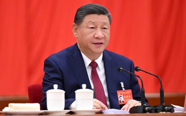 China redefine o futuro com plano de 5 anos focado em IA e semicondutores 5 Homem em reunião formal com terno azul escuro e cortina vermelha ao fundo