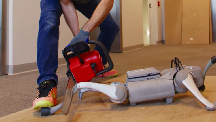 Skild Brain mostra como robôs superam desafios físicos extremos com inteligência adaptativa 1 Pessoa manipulando um robô cinza desmembrado em corredor de escritório