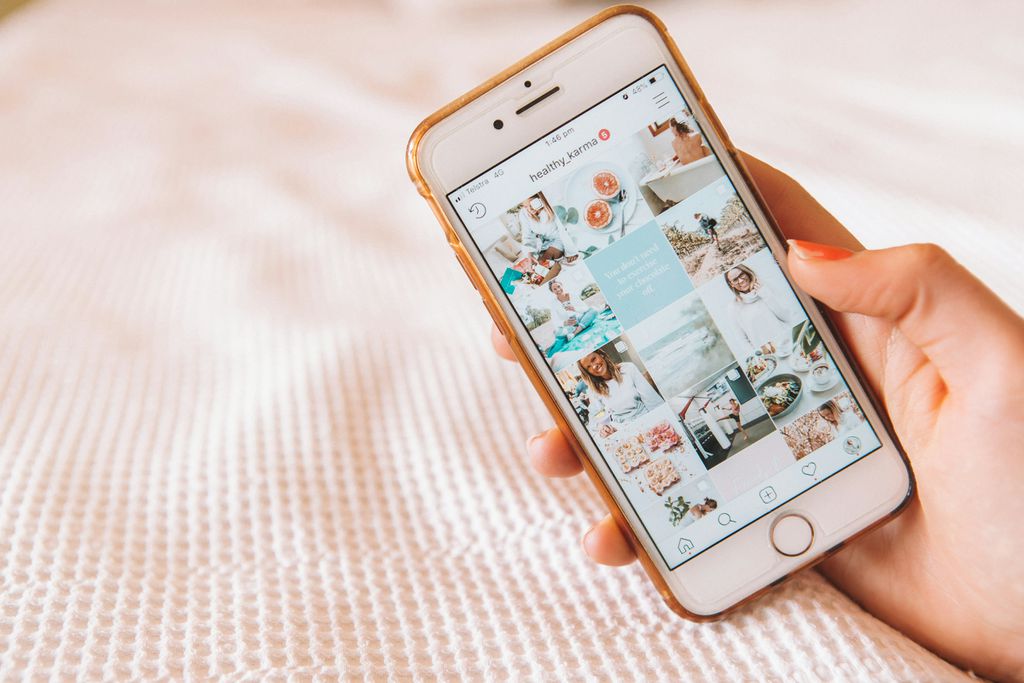 Brasileiros gastam quase 6 minutos editando cada post nas redes sociais 3 Mão segurando smartphone com interface do Instagram exibindo fotos em mosaico de várias categorias