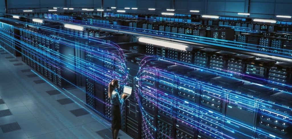 Oracle em crise Profunda: ações despencam 30% no pior trimestre em 20 anos 1 Corredor interno de data center moderno com racks de servidores e profissional com notebook