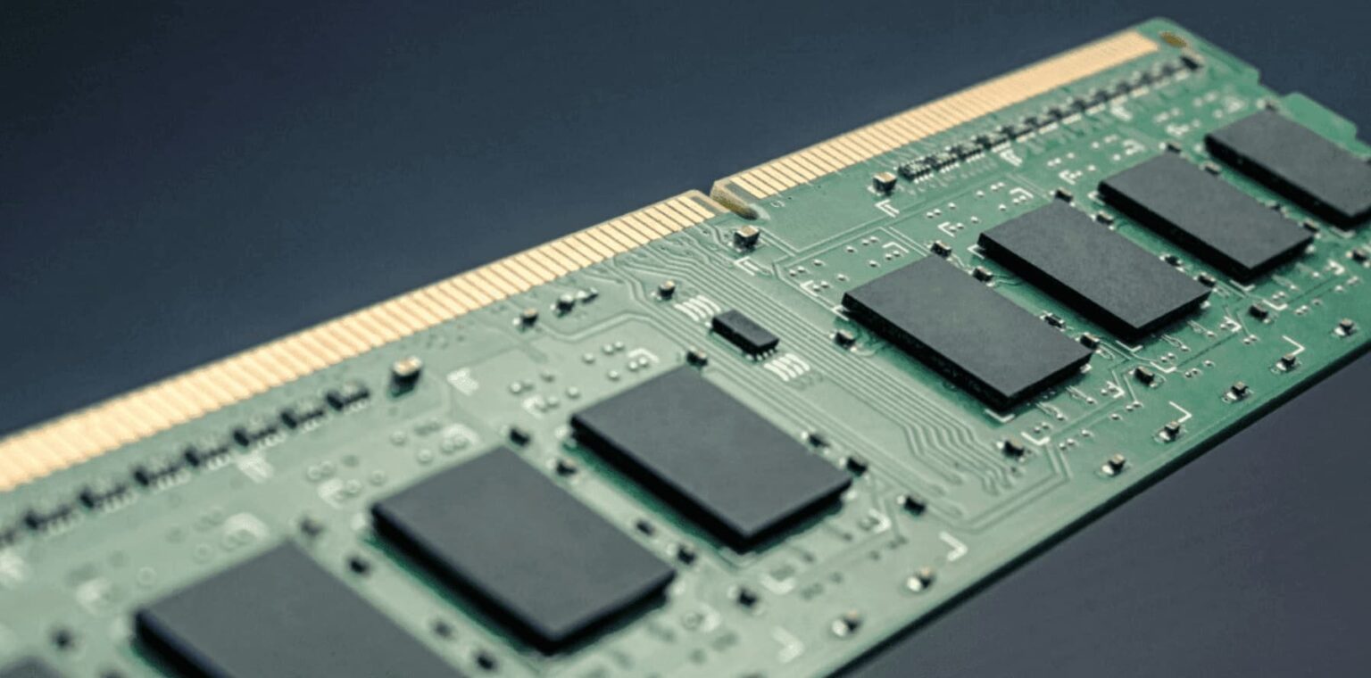Módulo de memória RAM DDR5 de cor verde, com chips pretos e conectores dourados, em close sobre fundo escuro