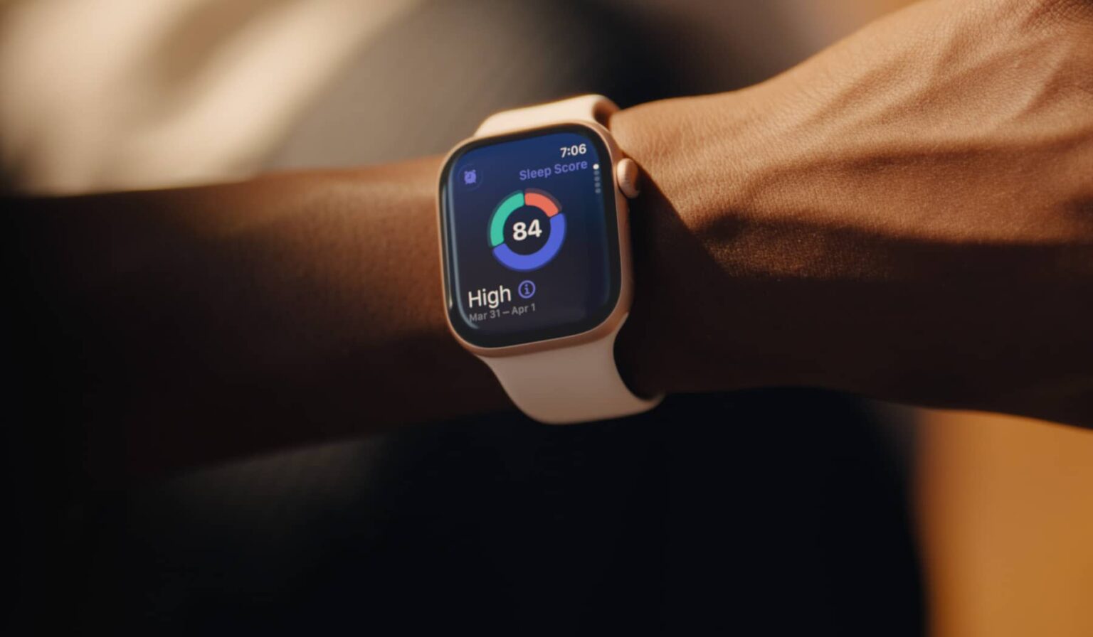 Apple Watch no pulso de uma pessoa exibindo a pontuação de sono 84 com classificação alta na tela