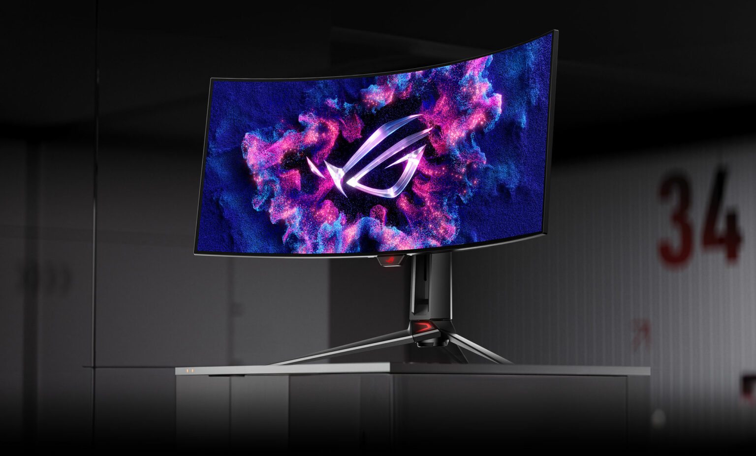 Monitor gamer curvo ASUS ROG com logo ROG na tela, exibido em suporte preto sobre fundo escuro