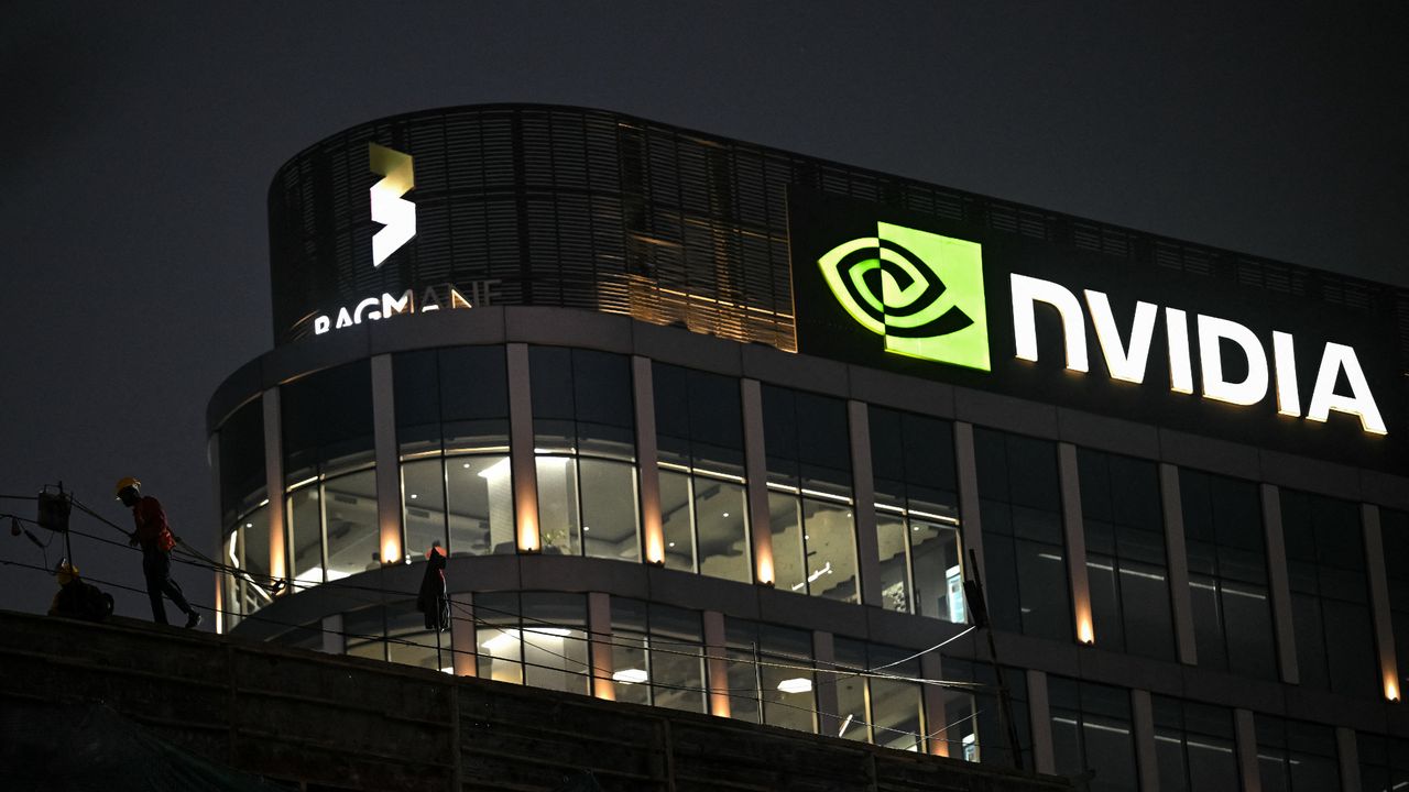 Fachada do prédio corporativo Nvidia à noite com logo iluminado e trabalhadores na cobertura