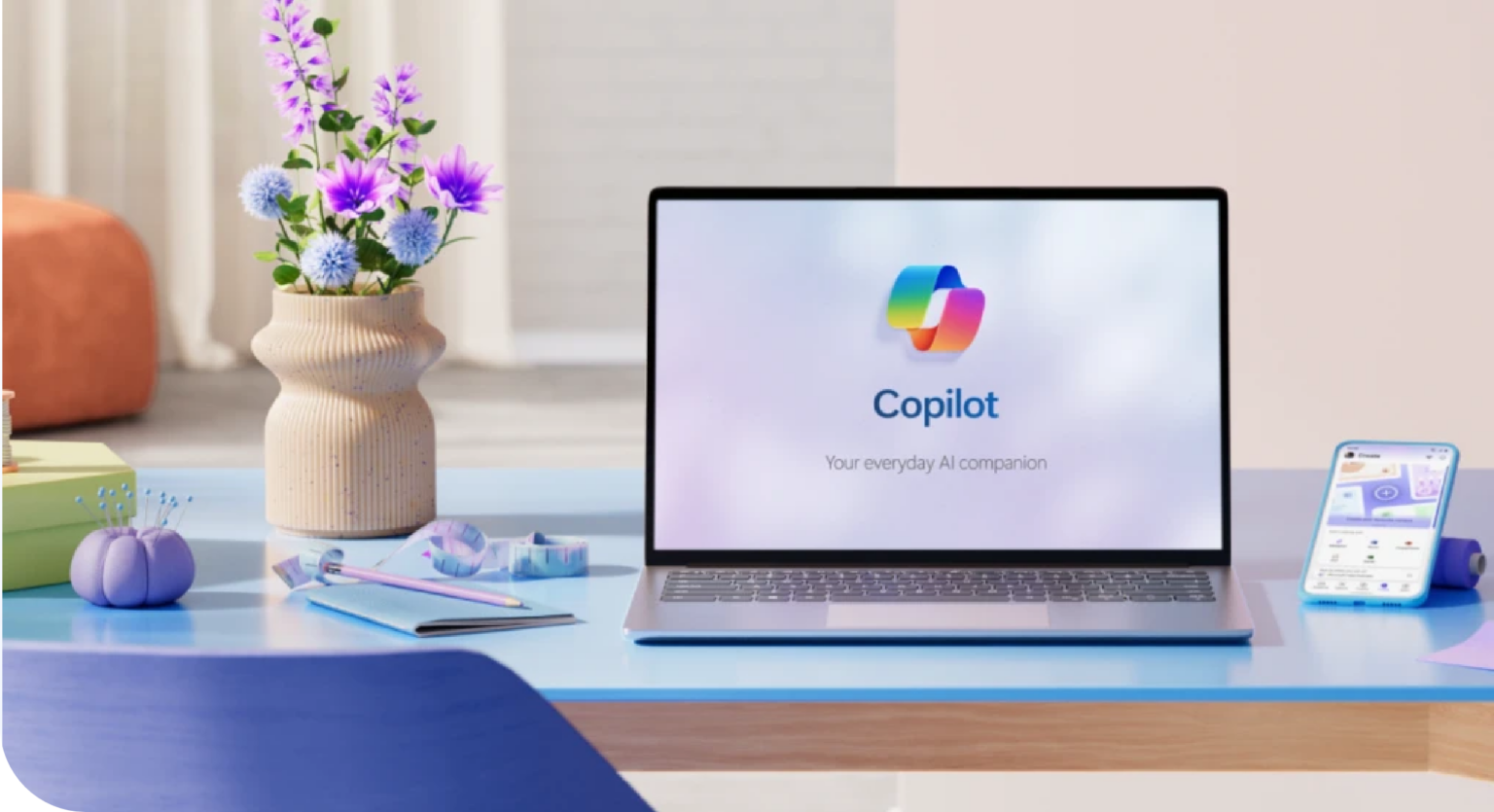 Notebook exibindo a tela inicial do Microsoft Copilot com a frase "Your everyday AI companion", sobre uma mesa azul decorada com vaso de flores e um smartphone