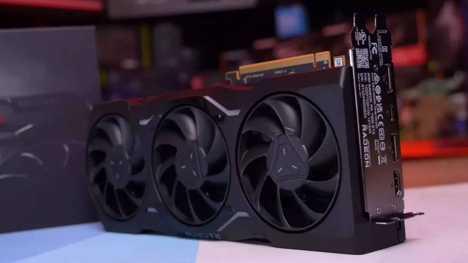 Placa de vídeo AMD Radeon preta com três ventoinhas e logotipo Radeon visível na lateral, apoiada sobre uma superfície clara