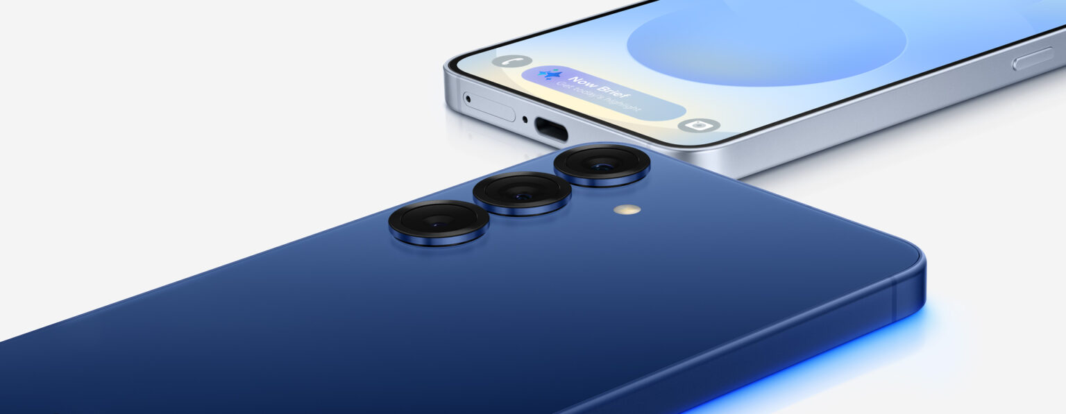 Smartphone Samsung Galaxy azul-marinho visto por trás com três câmeras traseiras, e outro aparelho de tela ligada ao fundo mostrando notificações