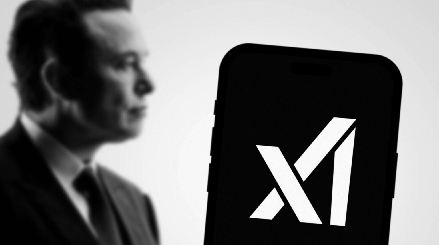 Homem de perfil desfocado em tom preto e branco ao lado de smartphone com o logotipo branco da xAI na tela preta