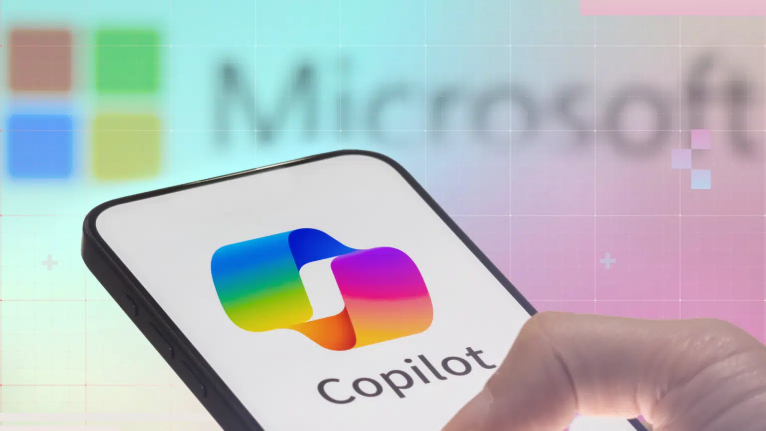 Smartphone com logo do Copilot da Microsoft na tela, sobre fundo com o logo da Microsoft desfocado