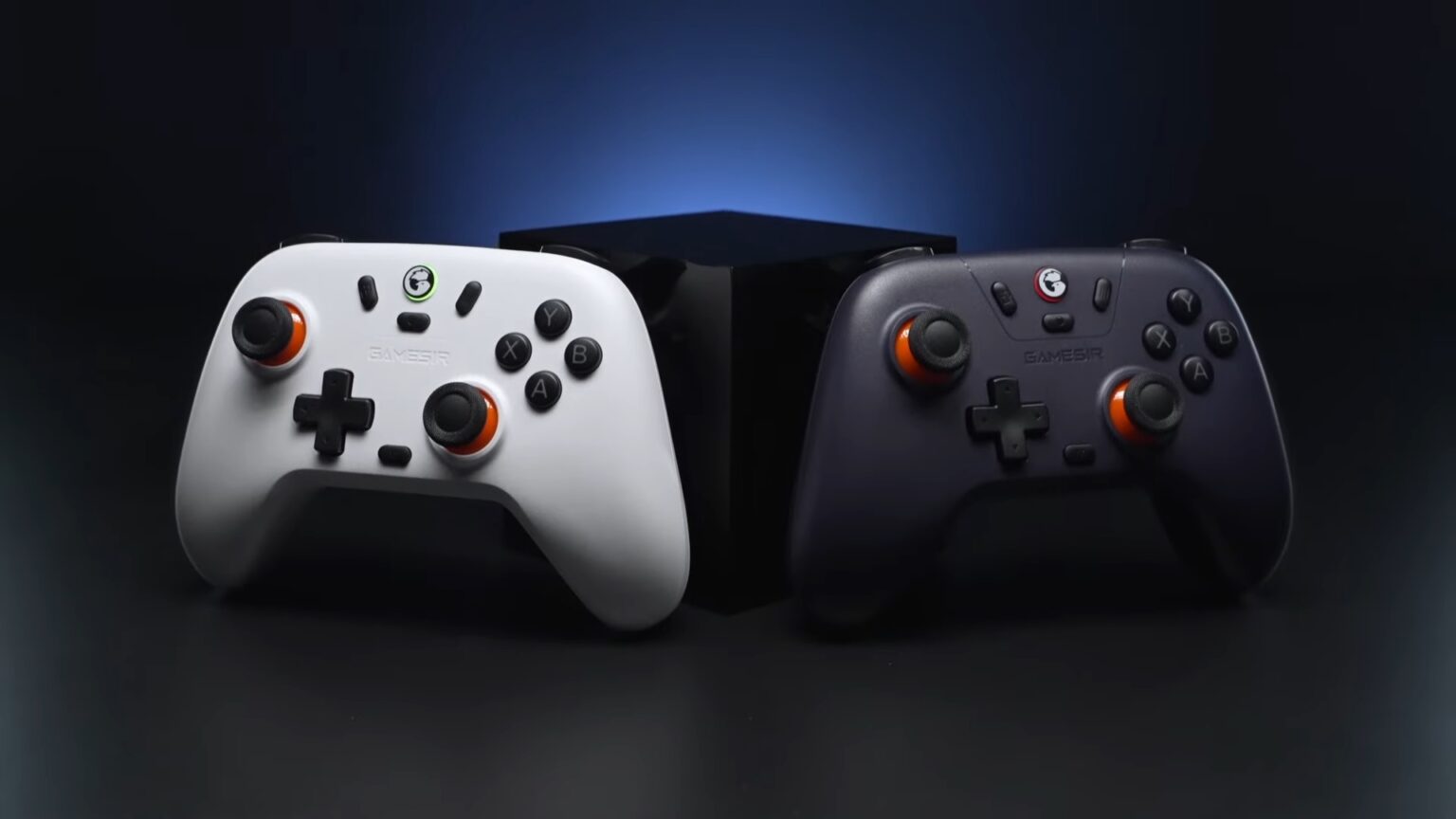 Dois controles de videogame sem fio, um branco e outro preto, com detalhes laranja, lado a lado diante de um fundo escuro com iluminação azul