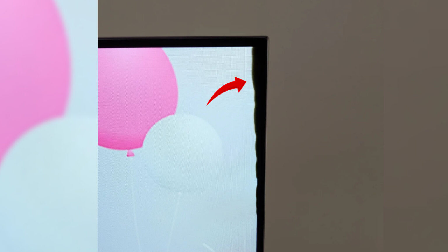Monitor com tela mostrando balões rosa e azul claro, com seta vermelha apontando para mancha escura na borda direita, indicando delaminação