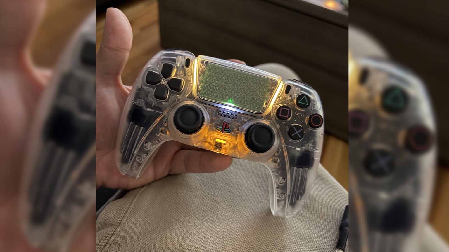 Controle DualSense do PS5 com carcaça transparente e iluminação amarela, segurado por uma mão sobre o colo de alguém