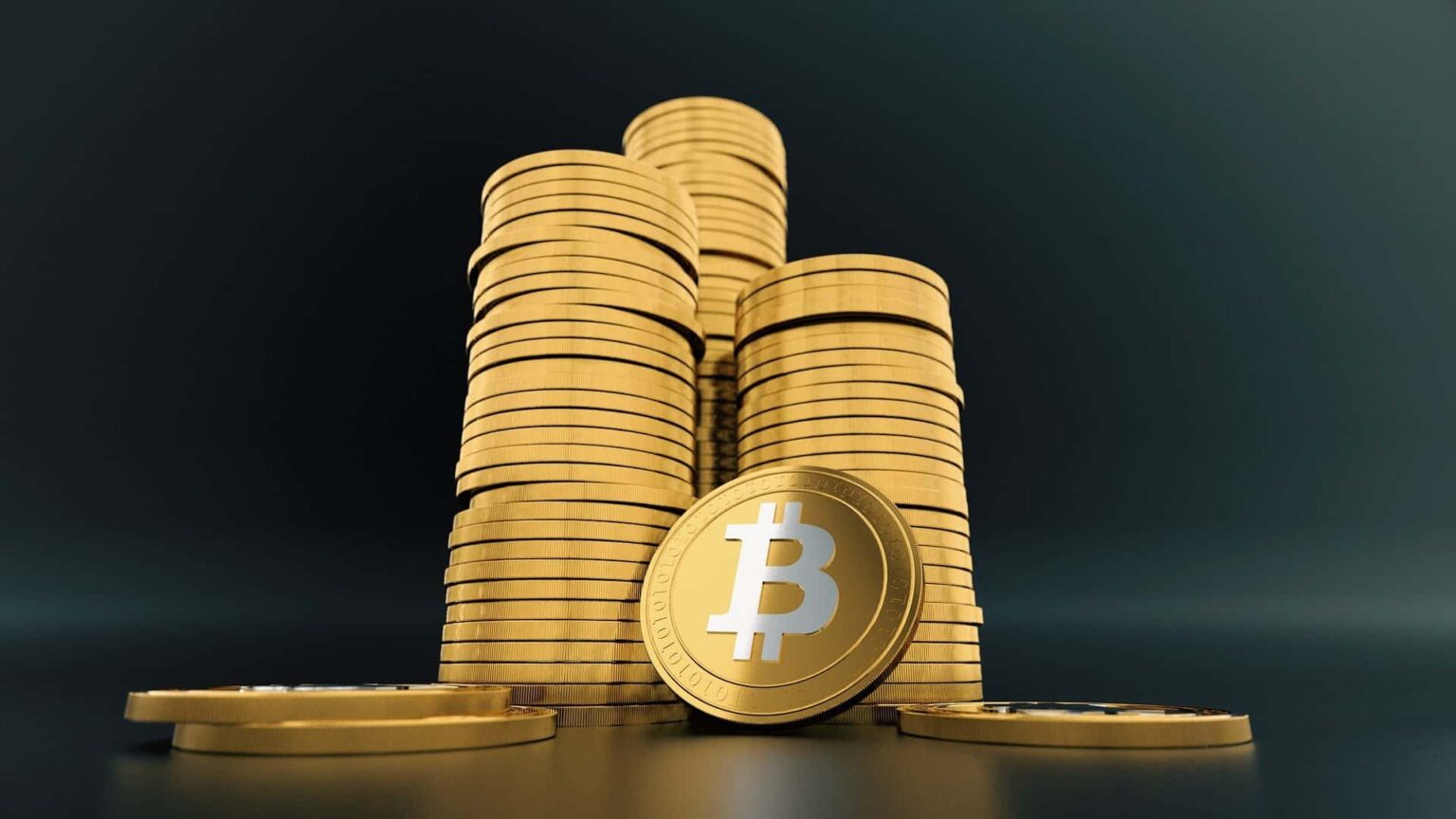 Pilhas de moedas douradas com o símbolo do bitcoin em destaque sobre um fundo escuro