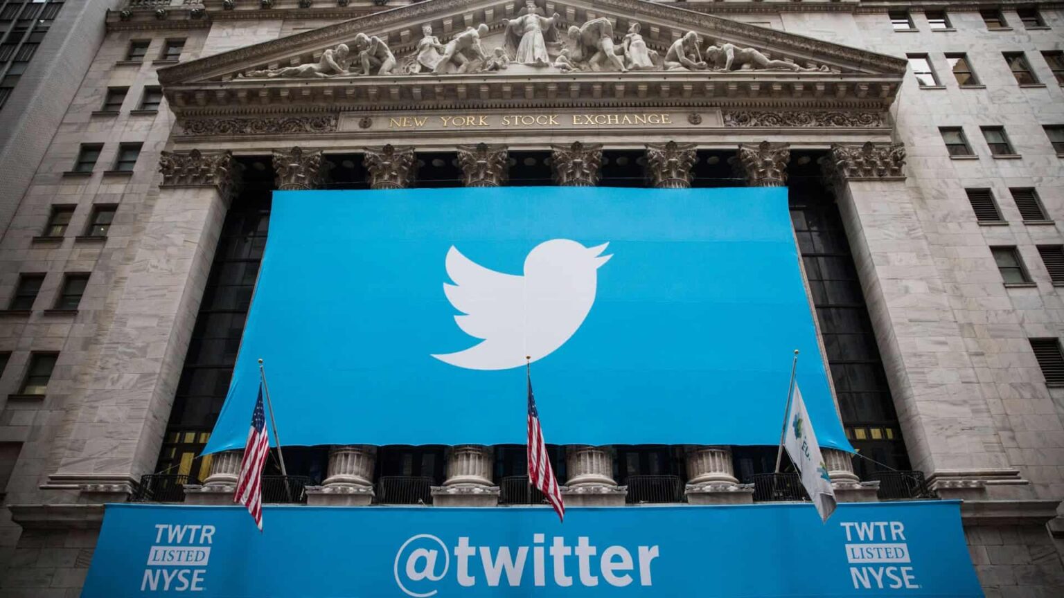 Fachada da Bolsa de Valores de Nova York com grande painel azul exibindo o logotipo de pássaro do Twitter e a faixa "@twitter", com a legenda "TWTR listed NYSE