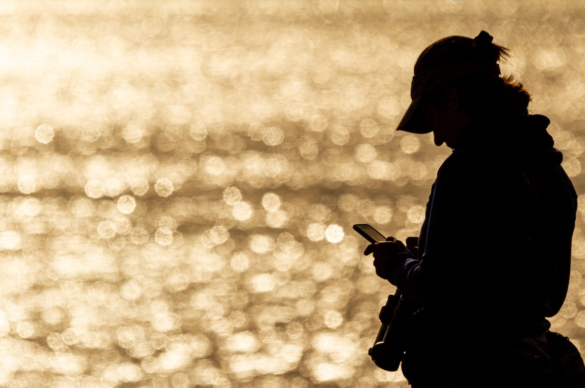 Pessoa usando celular na praia