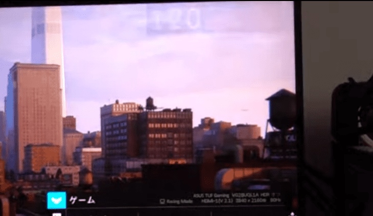 Tela de monitor ASUS TUF Gaming exibindo jogo em cena urbana com prédios, com menu OSD em japonês e resolução 3840 x 2160 a 60Hz via HDMI