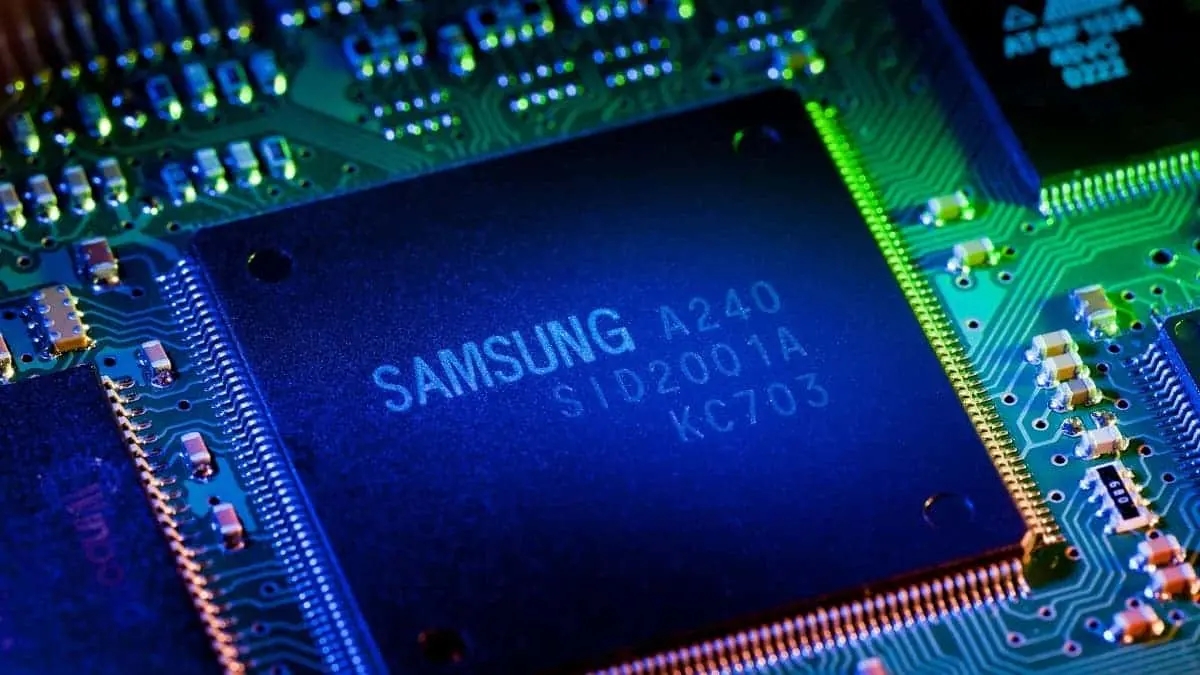 Chip da Samsung com a inscrição "SAMSUNG A240" sobre placa de circuito verde iluminada em azul