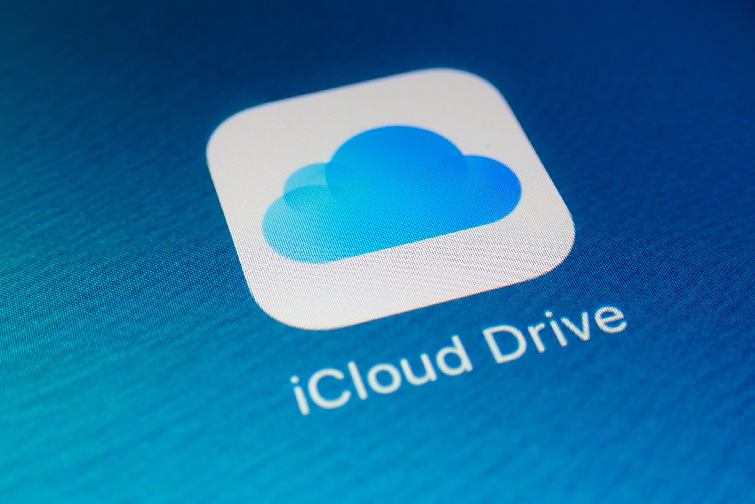 Ícone do aplicativo iCloud Drive, com nuvem azul sobre fundo branco arredondado, exibido na tela de um dispositivo Apple