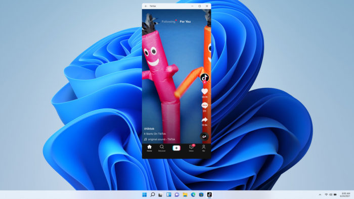 Captura de tela do TikTok em janela no Windows 11, mostrando um vídeo com bonecos infláveis de tubo rosa e laranja sobre o fundo de papel azul