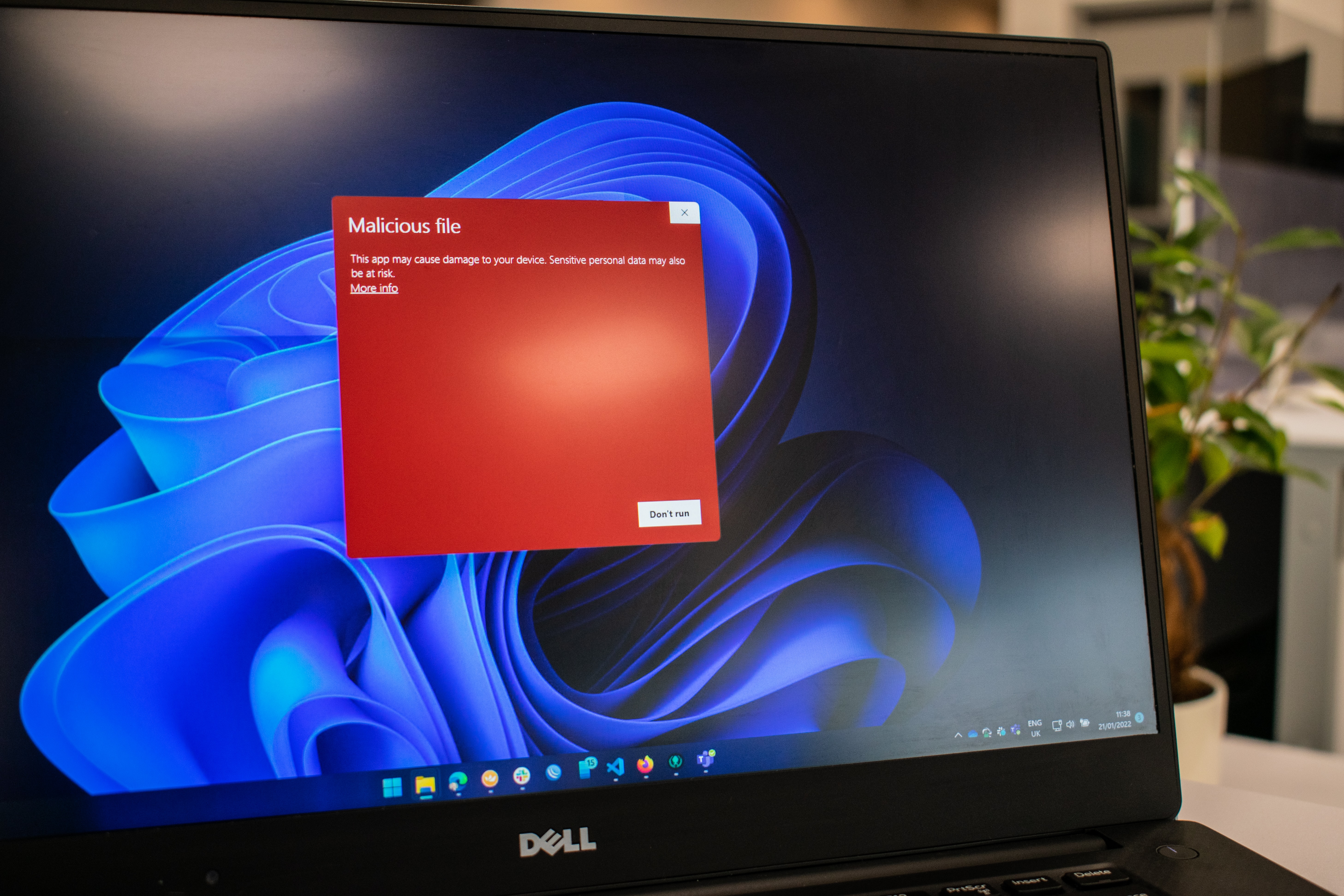 Notebook Dell exibindo alerta vermelho de "Malicious file" sobre o papel de parede azul do Windows 11, com o texto "Don't run