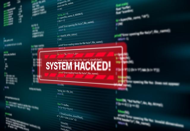 Ilustração de código-fonte em tela escura com um alerta vermelho em destaque que diz "SYSTEM HACKED!", sugerindo invasão de sistema