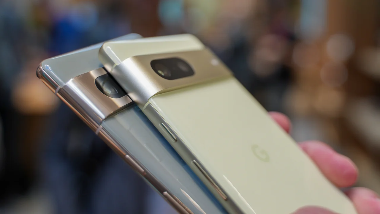 Dois smartphones Google Pixel, um verde-claro e outro cinza, lado a lado na mão, mostrando a faixa de câmera metálica na traseira