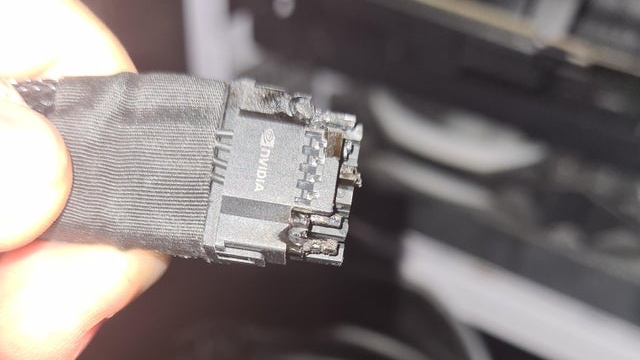 Conector de alimentação preto com logotipo NVIDIA, mostrando pinos danificados e marcas de derretimento e queimadura na carcaça plástica
