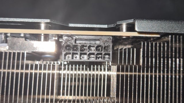 Conector de energia de 12 pinos de uma placa de vídeo com sinais de queimadura e derretimento, com a carcaça escurecida e os pinos danificados