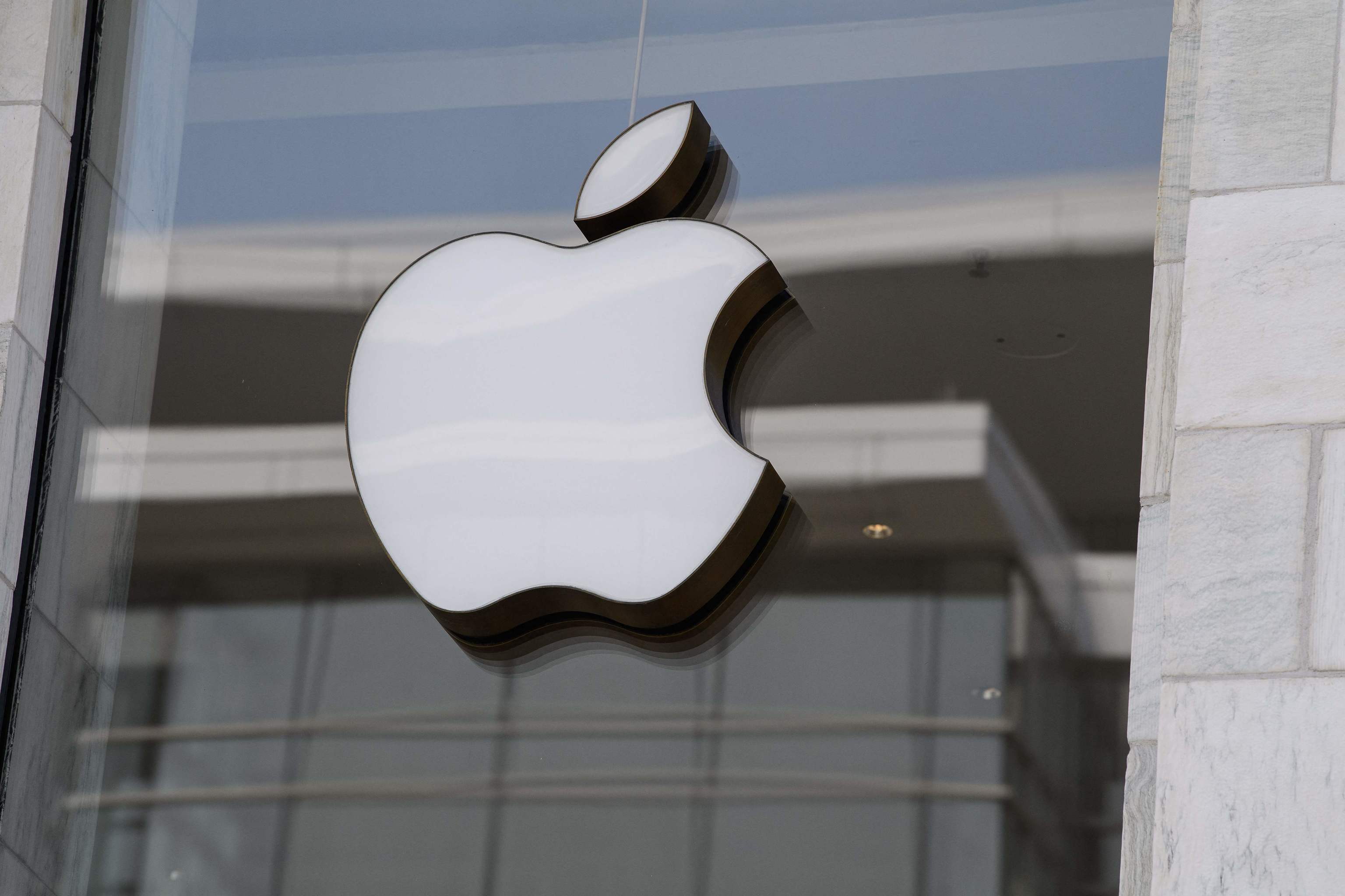 Logotipo da Apple, em branco e preto, fixado na fachada de vidro e pedra de uma loja da marca