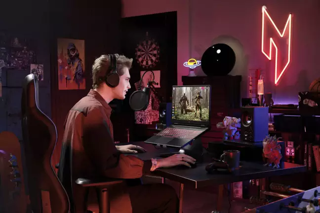 Homem jogando em notebook gamer Acer Nitro com teclado iluminado, headset e microfone em quarto temático com luz neon vermelha