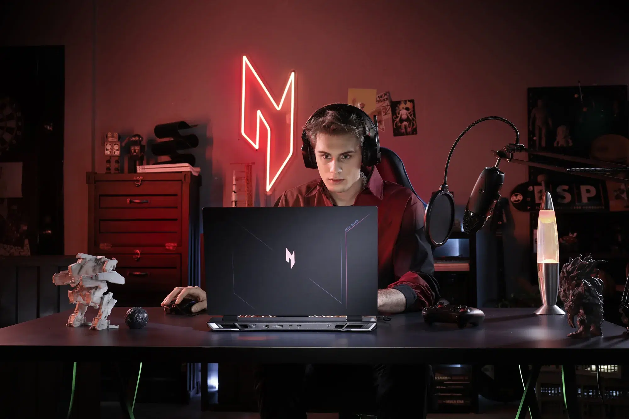 Notebook gamer Acer Nitro com logo Nitro na tampa, usado por jogador de fone de ouvido em setup vermelho e escuro com luz neon